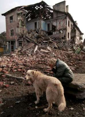 Woman and her Dog outside her bombed house, Grozny, Chechnya 1995. Photograph by Yuri Gripas  